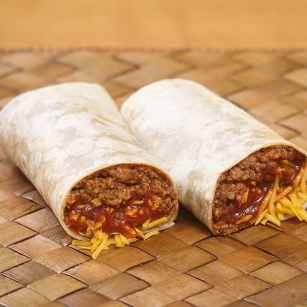 Two Naugles Tacos burritos, filled with ground beef, sauce, and shredded cheese, on a woven mat.