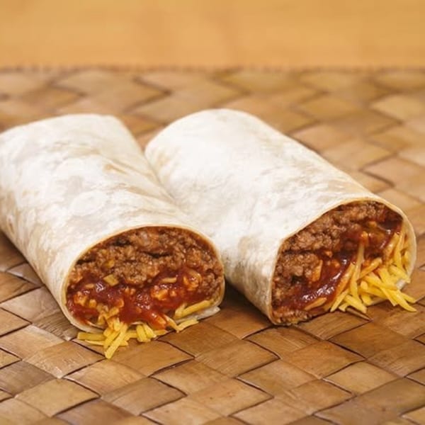 Two Naugles Tacos burritos, cut in half, revealing ground beef, sauce, and shredded cheese.