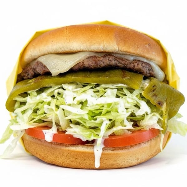 Cheeseburger with melted cheese, green chiles, shredded lettuce, tomatoes, and ranch dressing on a bun.